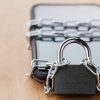 Smartphone chain with lock on wooden table showing mobile app security