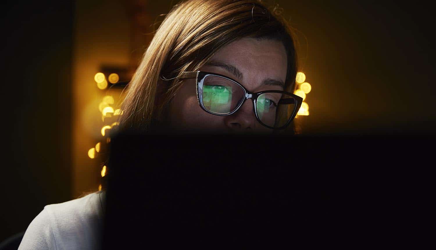 Woman in eyeglasses looking at monitor showing fraud scams with targeted links