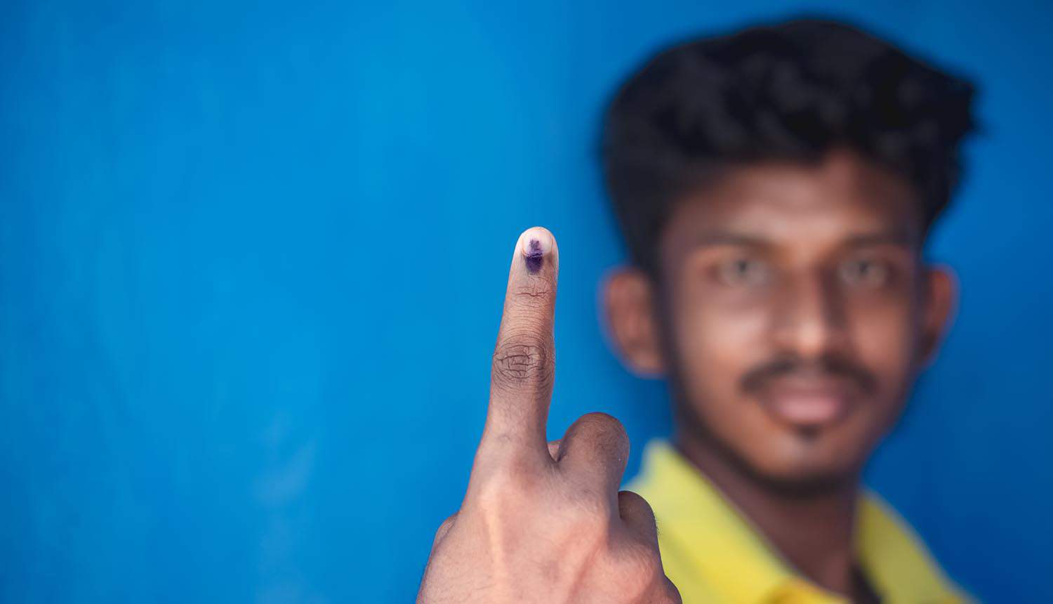 Indian voter showing his hand with voting sign and ink showing Aadhaar link to voter ID