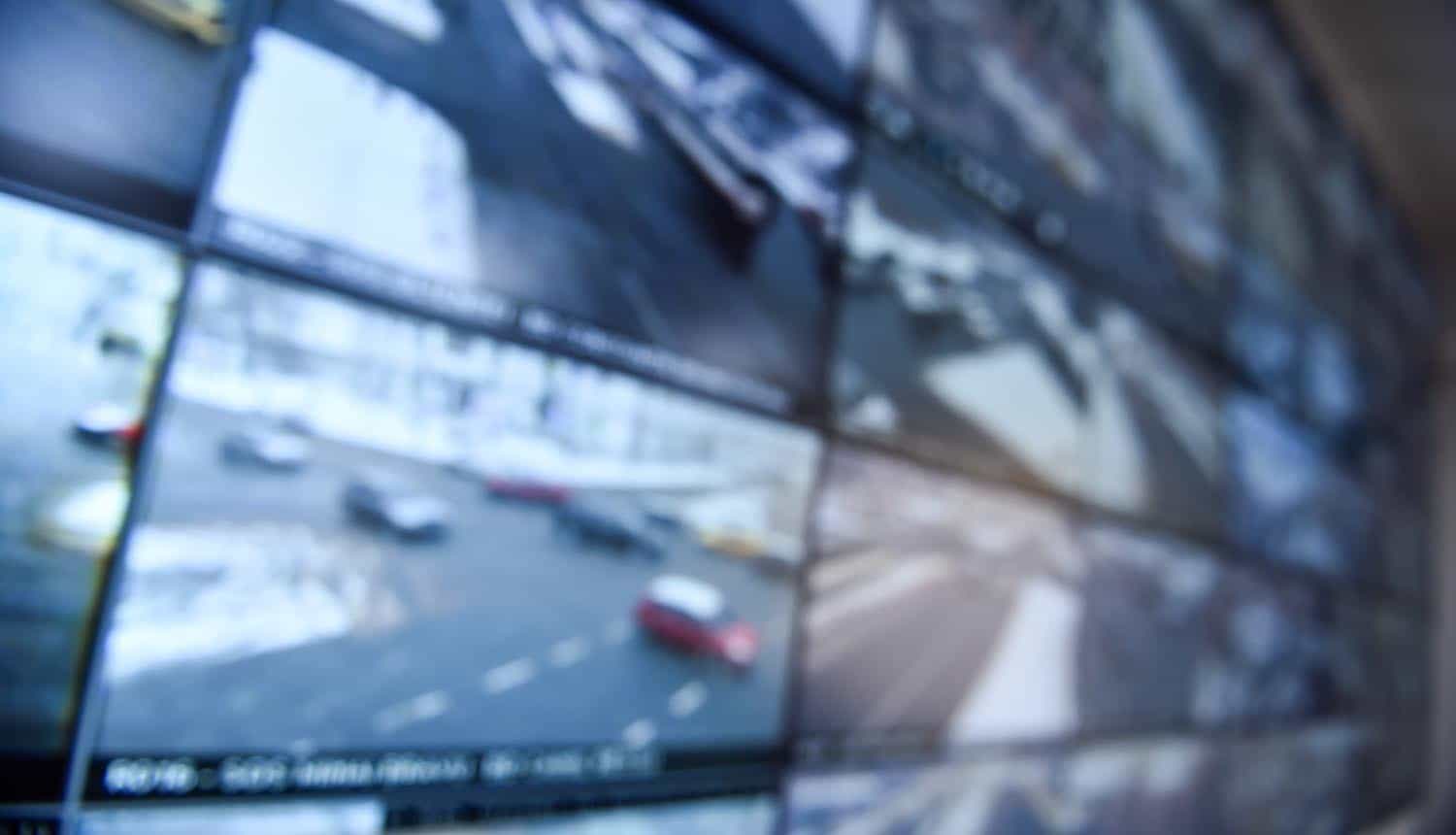Unfocused image with security surveillance monitors in command center showing UK police data stolen by Russian hackers