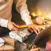 Close up of woman hands with credit card, gifts, and laptop showing Grinch bots during holiday shopping