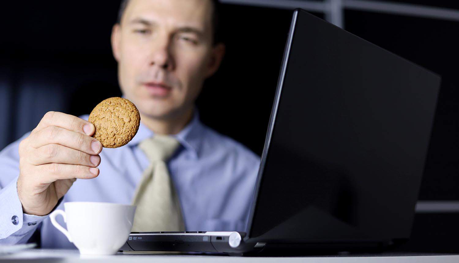 Man eating oatmeal cookie sitting at laptop showing cookieless future and privacy compliance