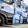 Fleet of commercial lorry trucks in row showing vehicle GPS tracker with hard-coded password vulnerabilities