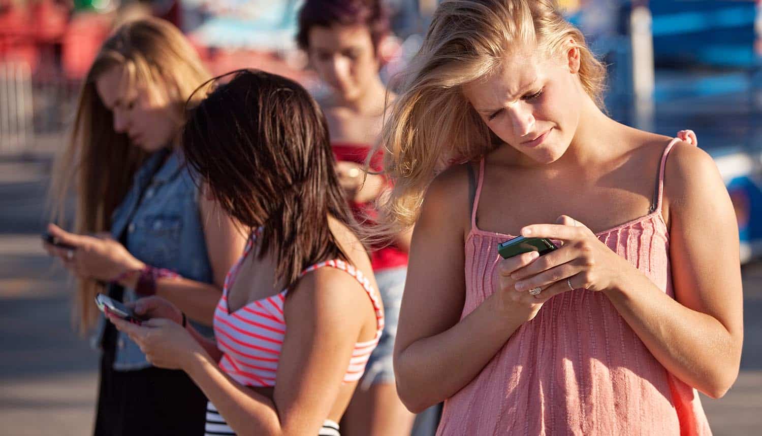 Teenagers using their phones looking stressed over Emergency Alert Systems with vulnerable software