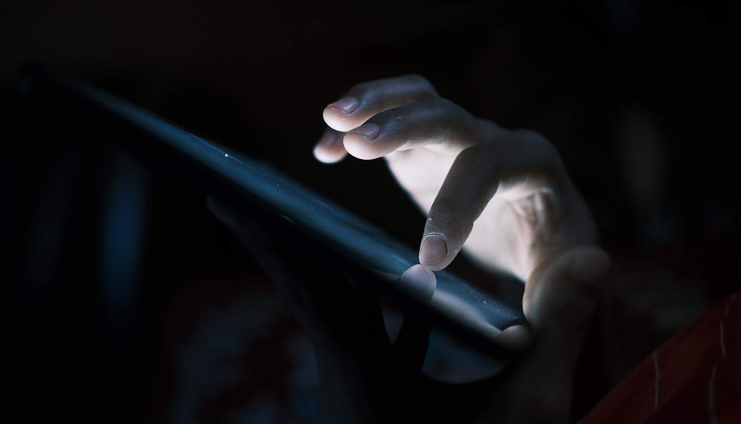 Close up of hand using smart phone at night showing Twilio hack exposed phone numbers of privacy messaging app Signal