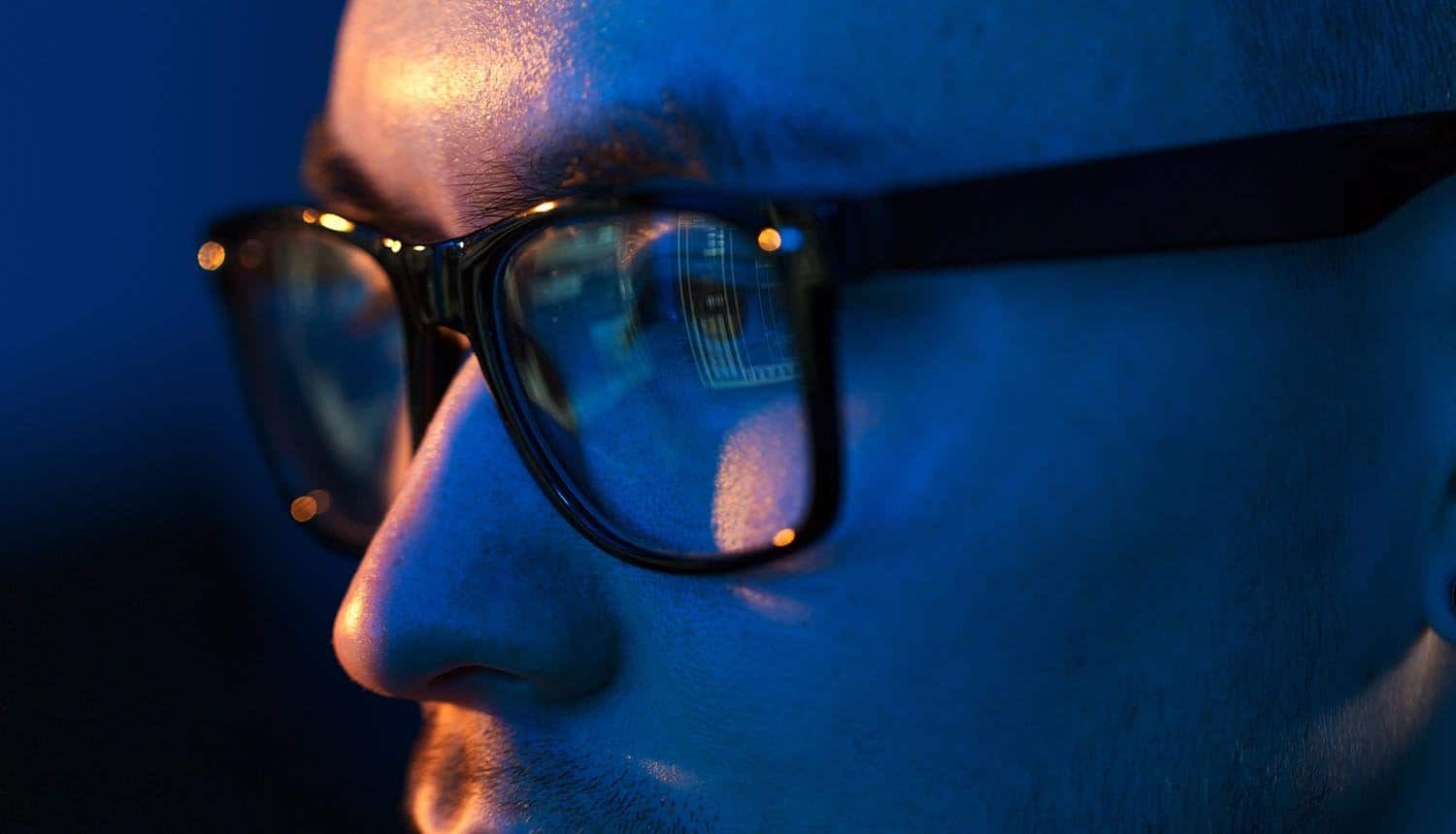 Close up of hacker eyes in glasses looking at computer screen