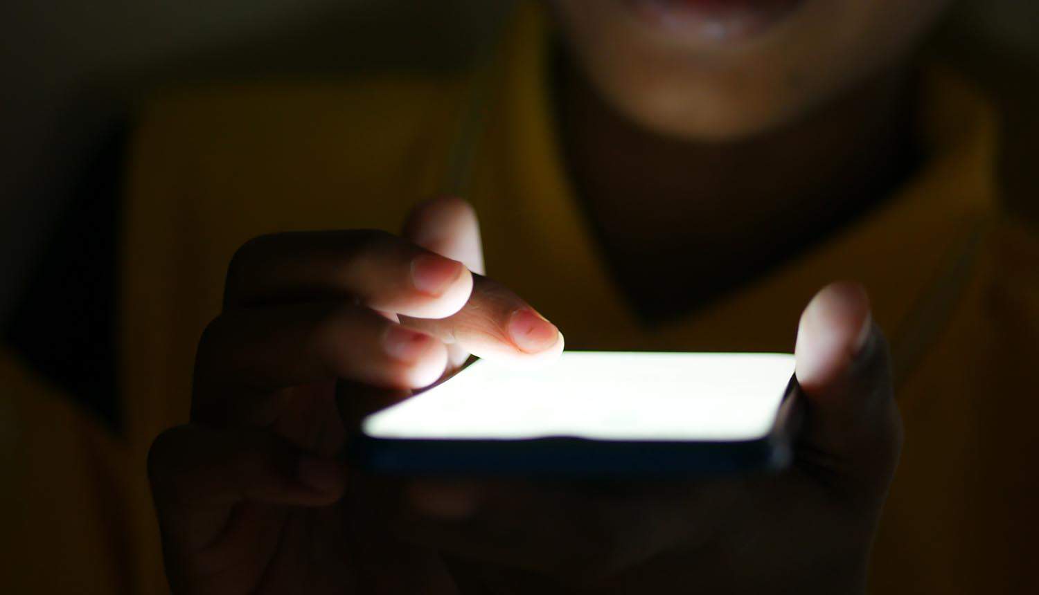 Close up of young man hand using smart phone at night showing data sharing of mobile apps