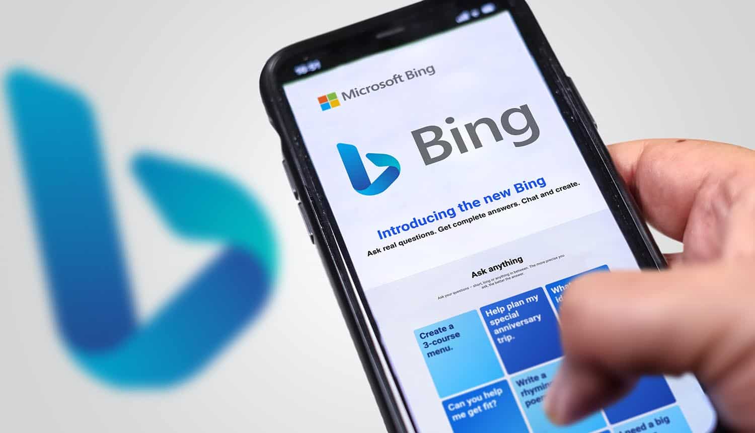 Hand holding a phone with Microsoft Bing website showing Bing search results