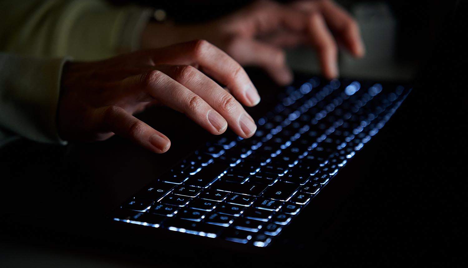 Hands of hacker typing on laptop keyboard showing MOVEit data breach by ransomware gangs