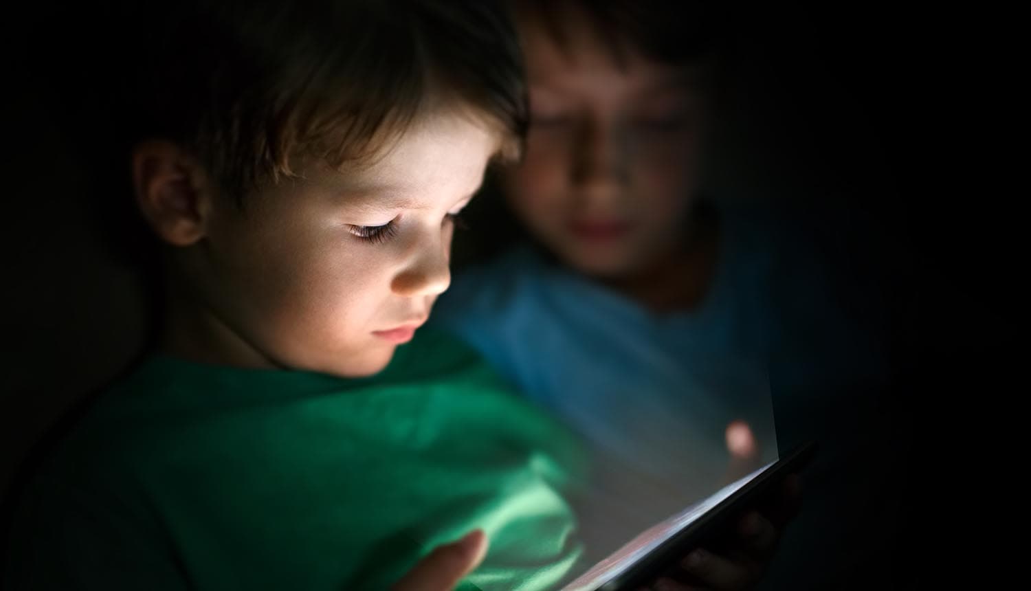 Brothers playing on tablet at night showing children's privacy online