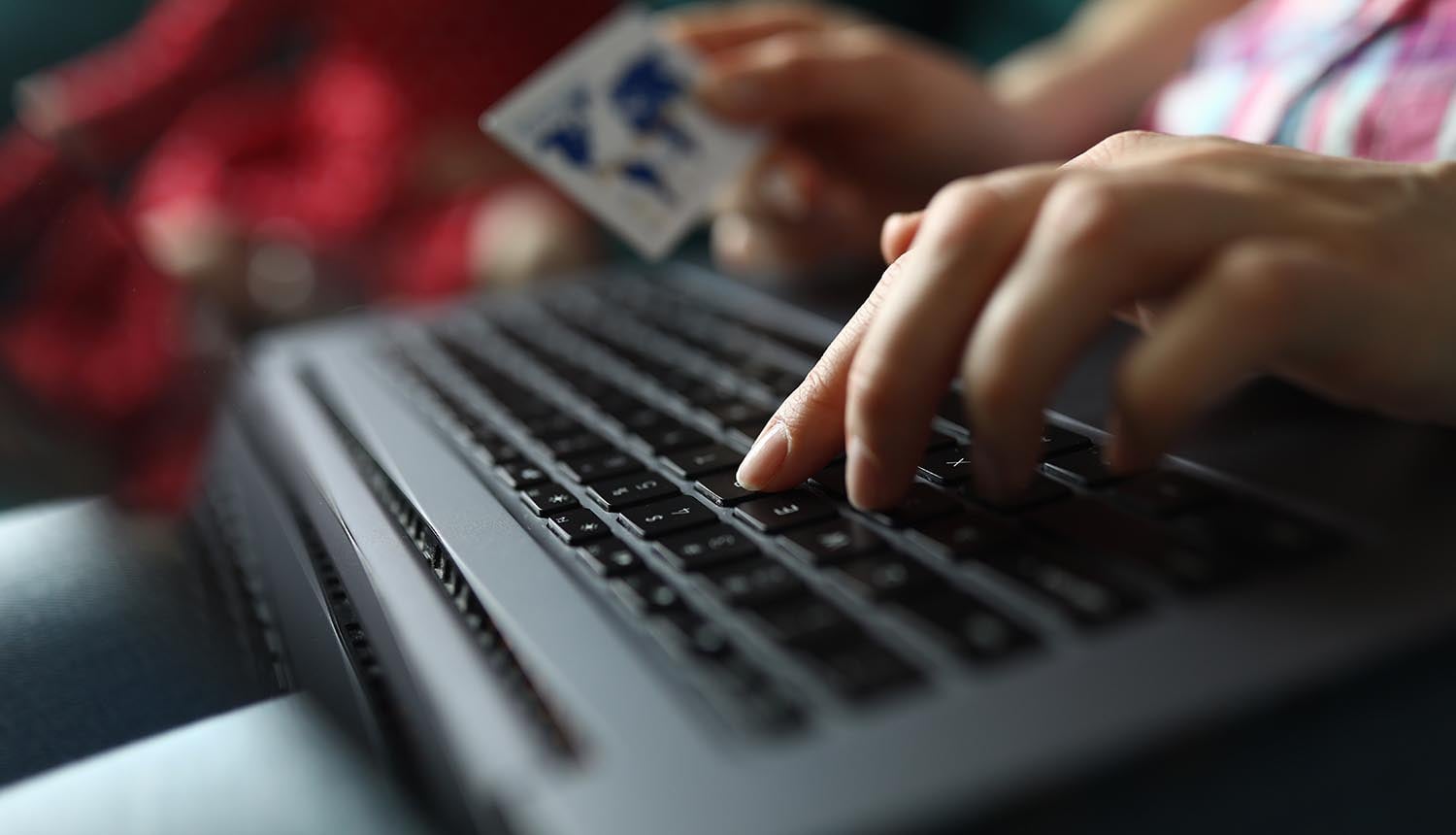 Hand holds credit card and works on keyboard showing data breach at payment providers
