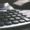 Calculator on table showing security budget and cost of data breach
