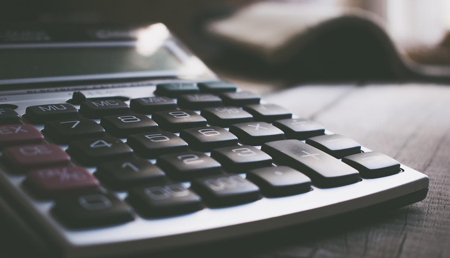 Calculator on table showing security budget and cost of data breach