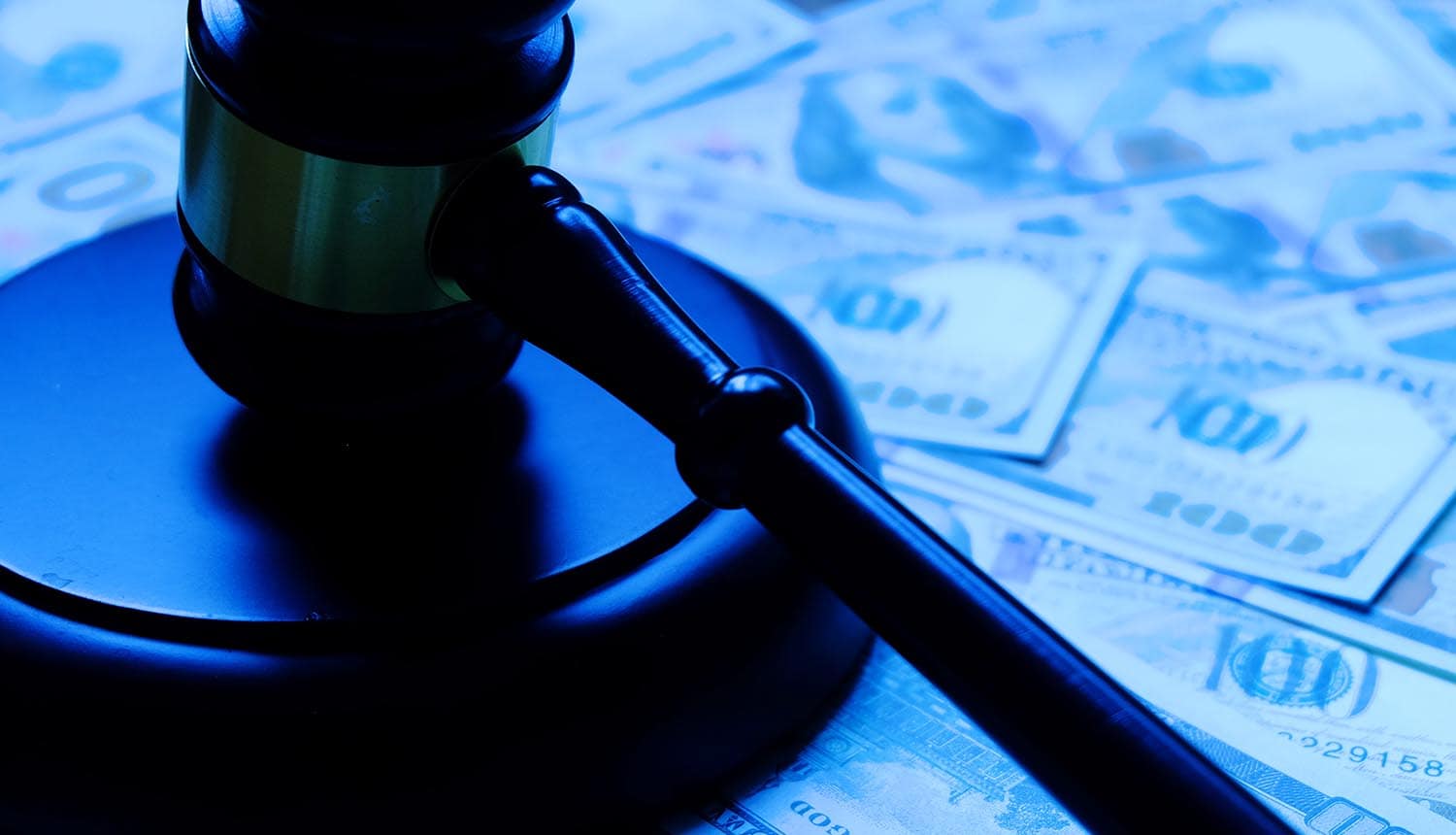 Wooden gavel lying on dollar notes showing cyber attack on art auctions