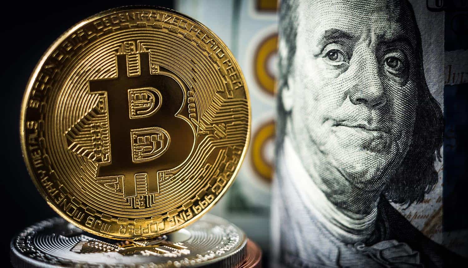 Gold bitcoin coin in front of dollar bills