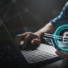 Man holding mobile phone at laptop showing data breach by unsecured API endpoint