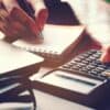 Hand using calculator showing cost of data breach