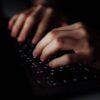 Hand typing on keyboard showing third party data breach of debt collection agency