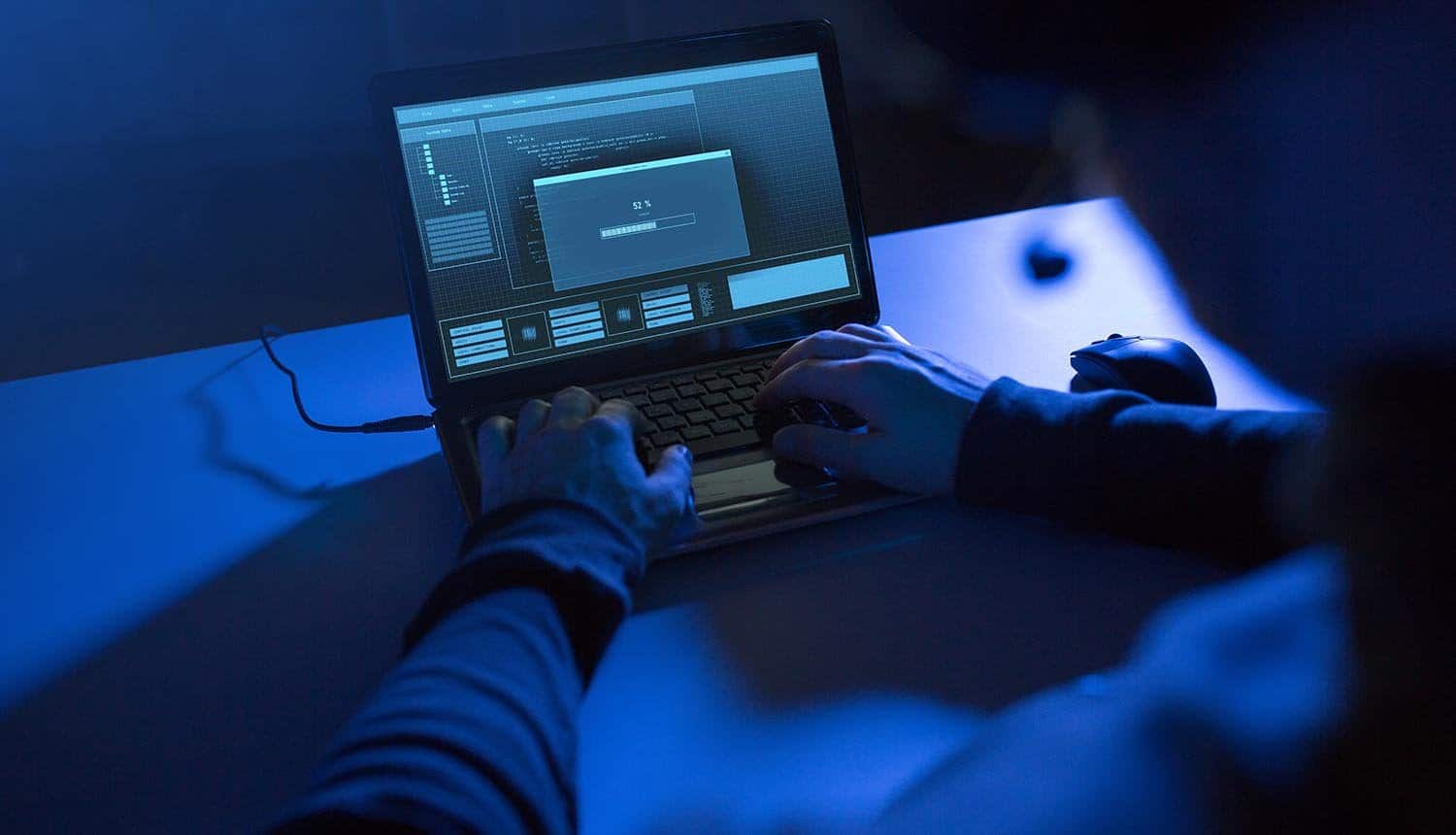 Hacker typing on laptop showing data breach of retail customers data