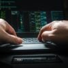 Hacker typing on keyboard showing data breach of insurance company