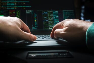Hacker typing on keyboard showing data breach of insurance company