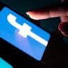 Smartphone with Facebook app showing Cambridge Analytica suit by Meta shareholders over FTC fines