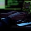 Hands typing on laptop showing cyber attack