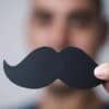 Man holding a fake moustache showing AI deepfakes