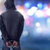 Hacker in handcuffs showing SIM farm for cybercrime