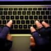 Hacker typing on laptop showing social engineering attacks