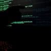 Hacker pointing to code on a monitor showing data breach and posted on dark web