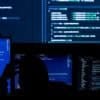Hacker working on machines showing data breach of customer records