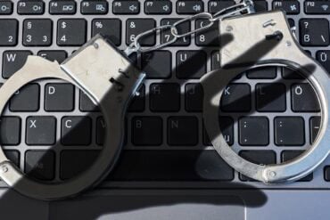 Handcuffs lying on keyboard showing law enforcement on scam accounts