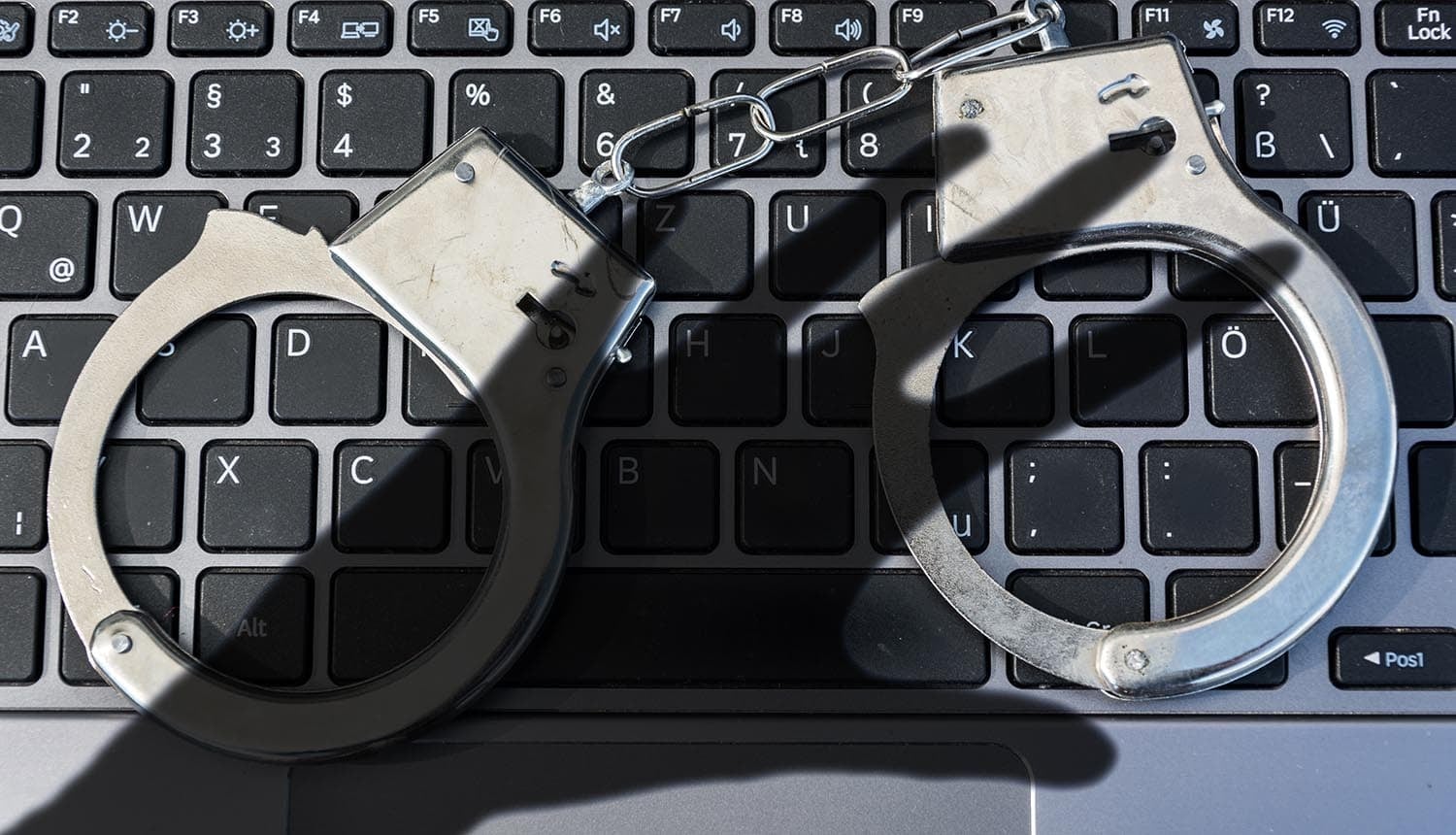 Handcuffs lying on keyboard showing law enforcement on scam accounts