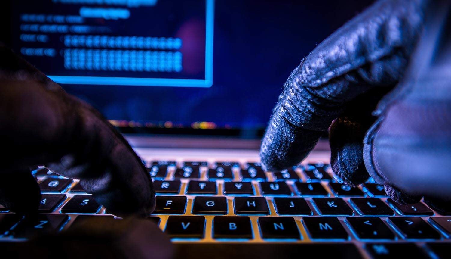 Hacker typing on keyboard showing data breach via social engineering
