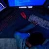 Hacker working on computer monitors showing cyber attack