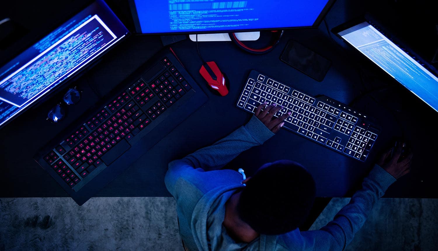 Hacker working on computer monitors showing cyber attack