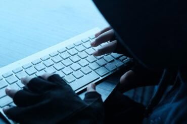 Hacker working on laptop showing data breach by ransomware gang