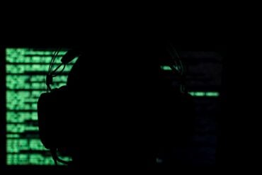 Hacker sitting in front of a monitor showing cyber attack on logistics provider