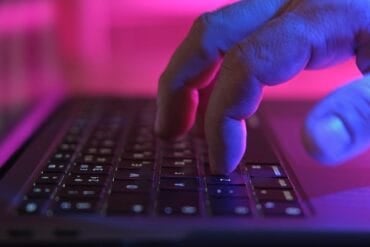 Person typing on laptop showing identity hijacking of AI workflows