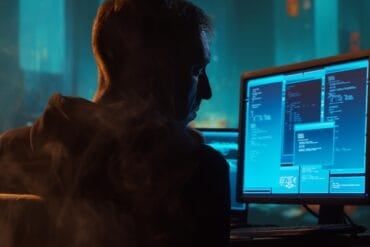 Hacker working on computer showing cyber attack on French supermarkets